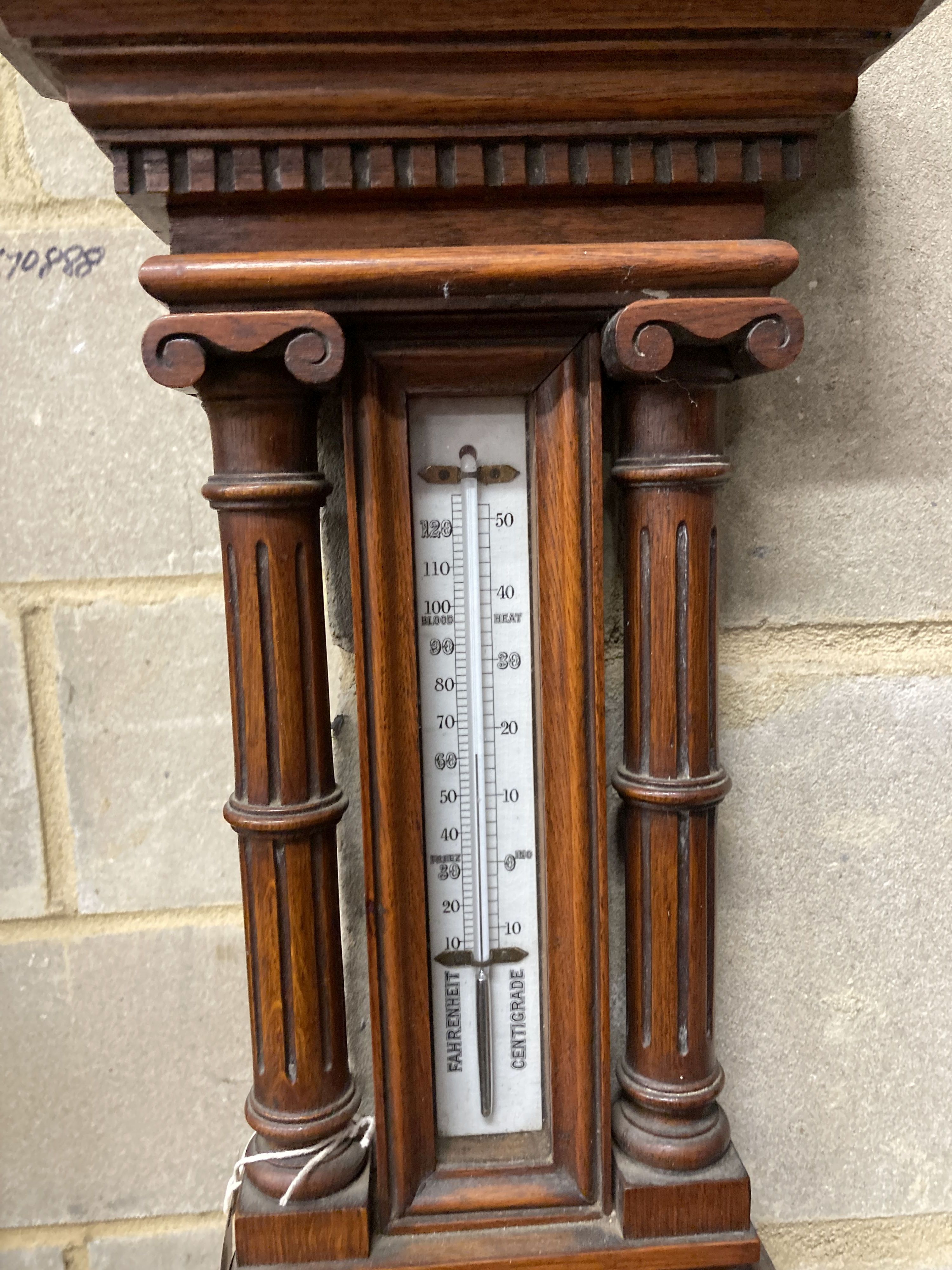 An Edwardian carved oak aneroid barometer and thermometer, height 80cm